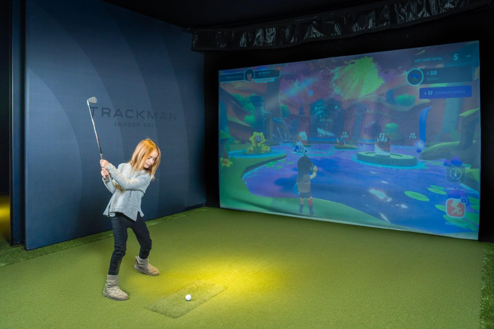 A junior golfer plays using Net Par's Trackman simulator